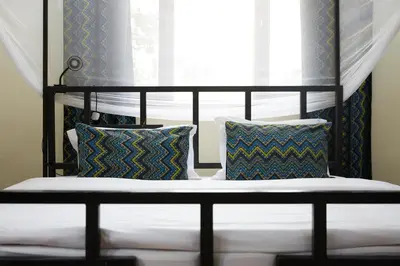 a bed with two pillows and a window at Viva Tanzania in Arusha