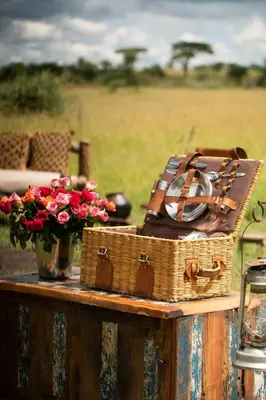 a suitcase and a vase of flowers on a table at Pumzika Luxury Safari Camp in Banagi