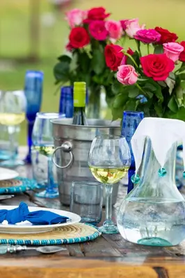 a wooden table with glasses of wine and flowers at Pumzika Luxury Safari Camp in Banagi