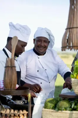 two chefs standing next to a table with vegetables at Pumzika Luxury Safari Camp in Banagi