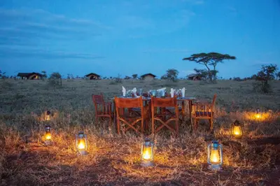 a table with candles and lights in a field at Pakulala Safari Camp - Ngorongoro in Ngorongoro