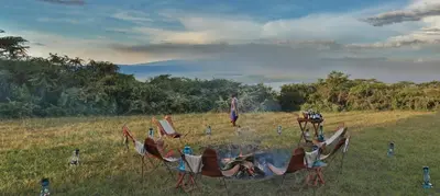 a group of chairs around a fire in a field at Pakulala Safari Camp - Ngorongoro in Ngorongoro