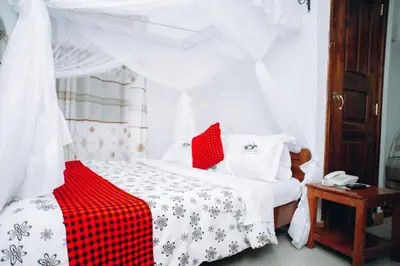 a bedroom with a bed with a red and white blanket at Arusha Giraffe Lodge in Arusha