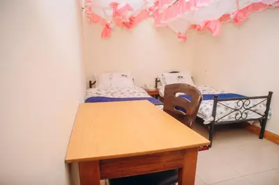 a room with two beds and a wooden table at Arusha Giraffe Lodge in Arusha