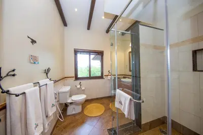 a bathroom with a toilet and a glass shower at The Retreat at Ngorongoro in Karatu