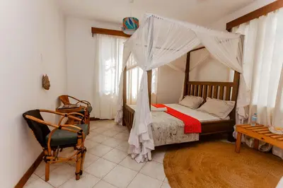 a bedroom with a canopy bed and a chair at City Villa in Arusha