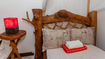 a bed with a wooden head board and a red and white pillow at City Villa in Arusha