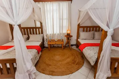 a bedroom with two beds with curtains and a table at City Villa in Arusha