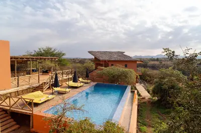 a swimming pool with lounge chairs and a house at Escarpment Luxury Lodge Manyara in Mto wa Mbu