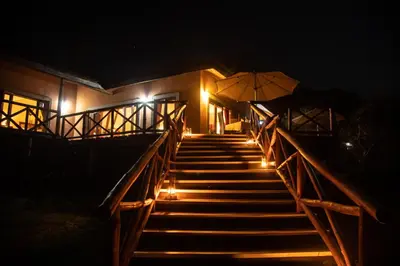 a stairway with an umbrella and lights at night at Escarpment Luxury Lodge Manyara in Mto wa Mbu