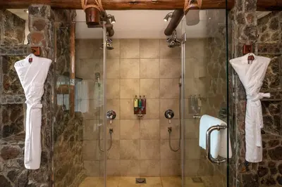 a bathroom with a shower with a glass shower stall at Lake Manyara Kilimamoja Lodge in Mto wa Mbu