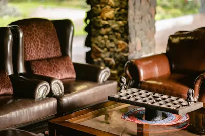a living room with two couches and a table with a chess at Lake Manyara Kilimamoja Lodge in Mto wa Mbu