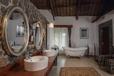 a bathroom with two sinks and a tub and mirrors at Lake Manyara Kilimamoja Lodge in Mto wa Mbu