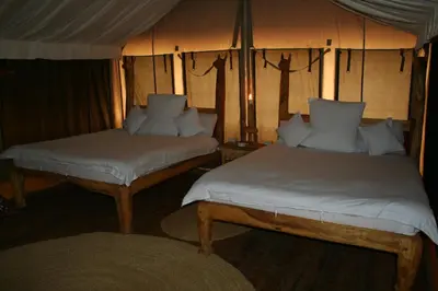 a bedroom with two beds and a table with a lamp at Roika Tarangire Tented Lodge in Kwa Kuchinia