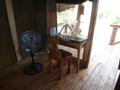 a room with a desk with a fan and a chair at Roika Tarangire Tented Lodge in Kwa Kuchinia