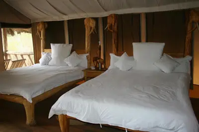 two beds in a bedroom with white sheets and pillows at Roika Tarangire Tented Lodge in Kwa Kuchinia