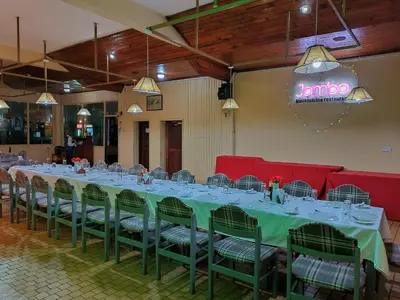 a long table with green chairs and a neon sign at Keys Hotel in Moshi
