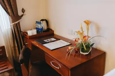 a wooden desk with a vase of flowers on it at Keys Hotel in Moshi