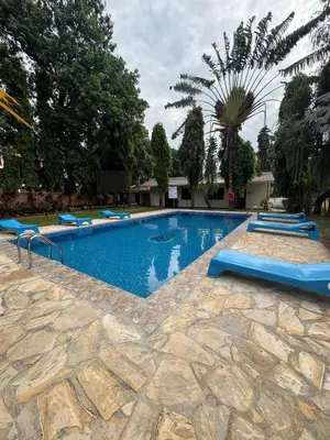 a large swimming pool with blue chairs in a yard at Keys Hotel in Moshi
