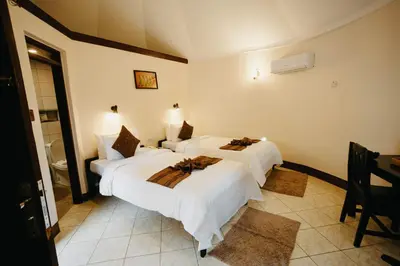 two beds in a hotel room with white sheets at Keys Hotel in Moshi