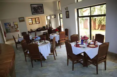 a dining room with tables and chairs with flowers on them at Sangana Lodge in Moshi