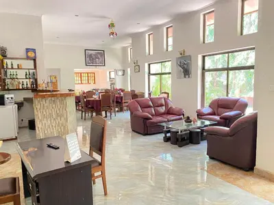 a living room with leather chairs and tables and a bar at Sangana Lodge in Moshi
