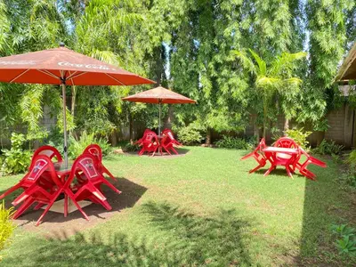 a group of red chairs and umbrellas in a yard at Sangana Lodge in Moshi