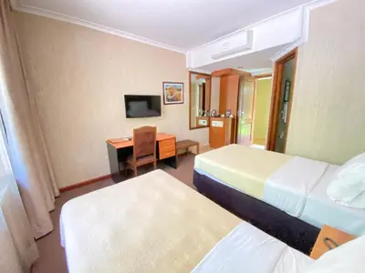 a hotel room with two beds and a desk at Sangana Lodge in Moshi