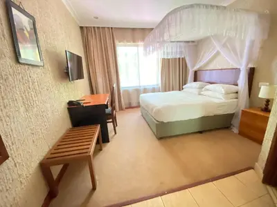 a bedroom with a bed and a desk and a bed at Sangana Lodge in Moshi
