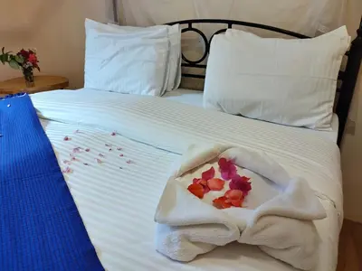 a white bed with a pile of towels on it at Tanzanice Farm Lodge in Karatu