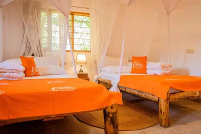 two beds in a room with orange sheets at Meru View Lodge in Usa River