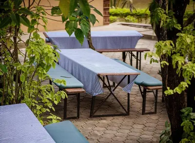 a row of blue tables and benches with trees at Meru View Lodge in Usa River