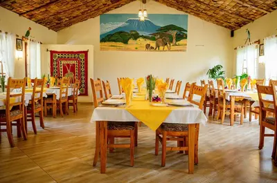 a dining room with tables and chairs with yellow table cloth at Meru View Lodge in Usa River