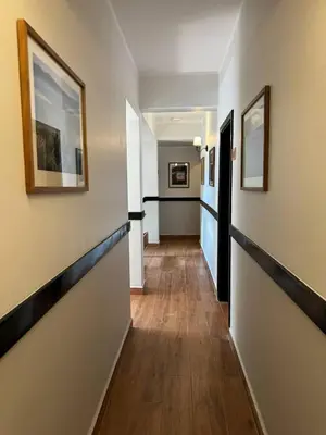 a hallway with white walls and wooden floors and paintings at Aishi Machame in Moshi