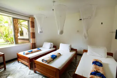 three beds in a room with a window at Keys Hotel Mbokomu Branch in Moshi