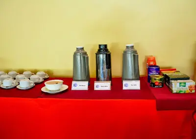 a red table with three bottles and cups on it at Keys Hotel Mbokomu Branch in Moshi