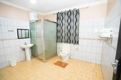 a bathroom with a shower and a toilet and a sink at Keys Hotel Mbokomu Branch in Moshi