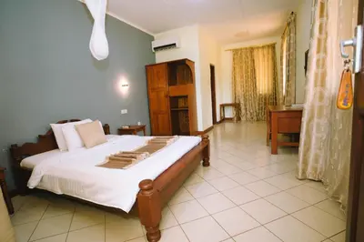 a bedroom with a large bed and a bathroom at Keys Hotel Mbokomu Branch in Moshi