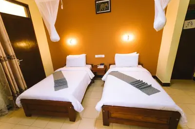 two beds sitting next to each other in a room at Keys Hotel Mbokomu Branch in Moshi