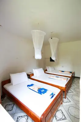 two beds in a room with white walls and lights at Keys Hotel Mbokomu Branch in Moshi