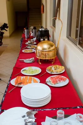 a long red table with plates of food on it at Keys Hotel Mbokomu Branch in Moshi