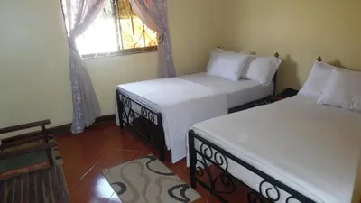 two beds in a room with a window at Bright Star Hotel & Safaris in Arusha