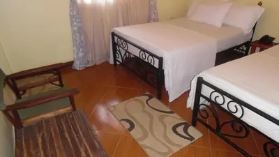 a room with two beds and a wooden floor at Bright Star Hotel & Safaris in Arusha