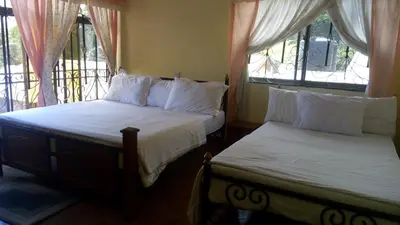 two beds in a room with two windows at Bright Star Hotel & Safaris in Arusha
