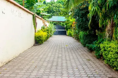 a brick path next to a white wall with a gate at Bright Star Hotel & Safaris in Arusha
