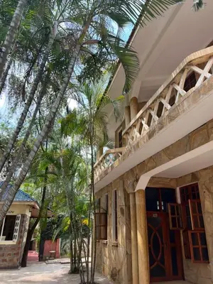 a building with palm trees in front of it at The Paradise Inn Kilimanjaro in Moshi