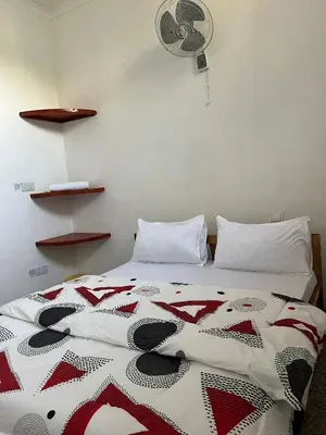 a bedroom with a bed with a red and white quilt at The Paradise Inn Kilimanjaro in Moshi