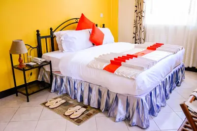a bedroom with a large bed with slippers on the floor at Crest Safari Lodge Bed and Breakfast in Arusha