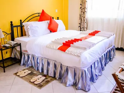 a bedroom with a large bed with slippers on the floor at Crest Safari Lodge Bed and Breakfast in Arusha