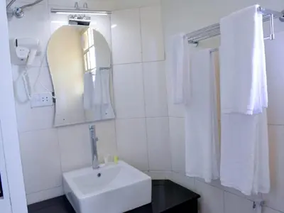 a white bathroom with a sink and a mirror at Crest Safari Lodge Bed and Breakfast in Arusha